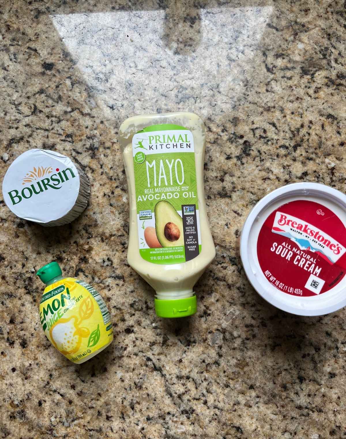 Boursing cheese, may, sour cream and a lemon bottle on a table