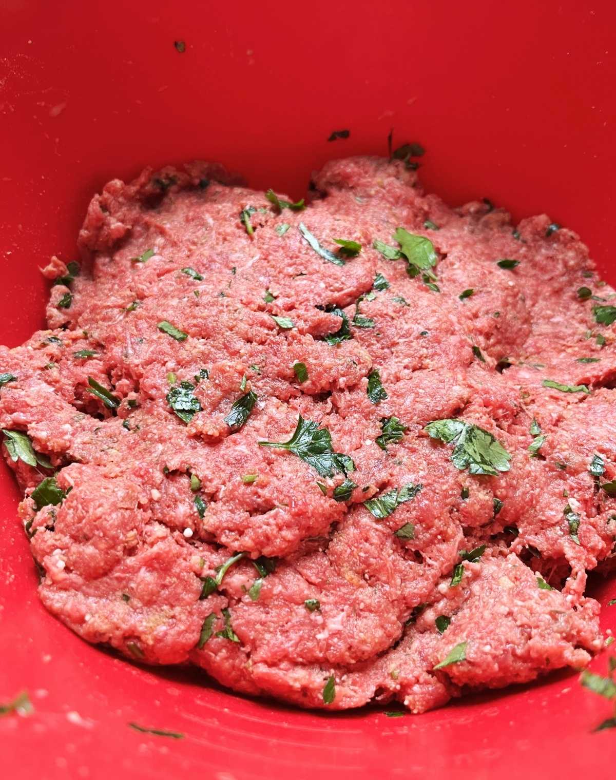 A loaf of ground meat and ingredients in a mixing bowl