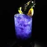 Refreshing blue mocktail with ice and pineapple garnish on black background.