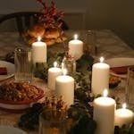 Warm candlelit dinner setting with festive and elegant decorations on a table, ideal for holiday celebrations.